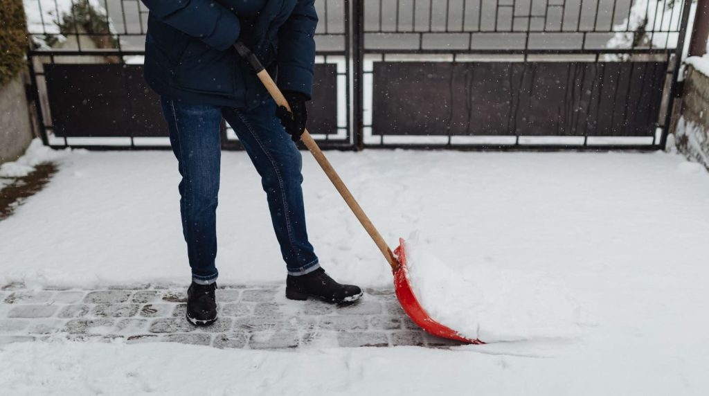 Osoba lopatom čisti sneg u dvorištu
